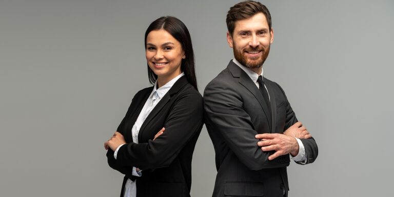 Homem e mulher usando roupa social de braços cruzados sorrindo