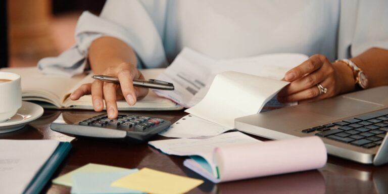 Mulher usando calculadora em uma mesa cheia de papéis